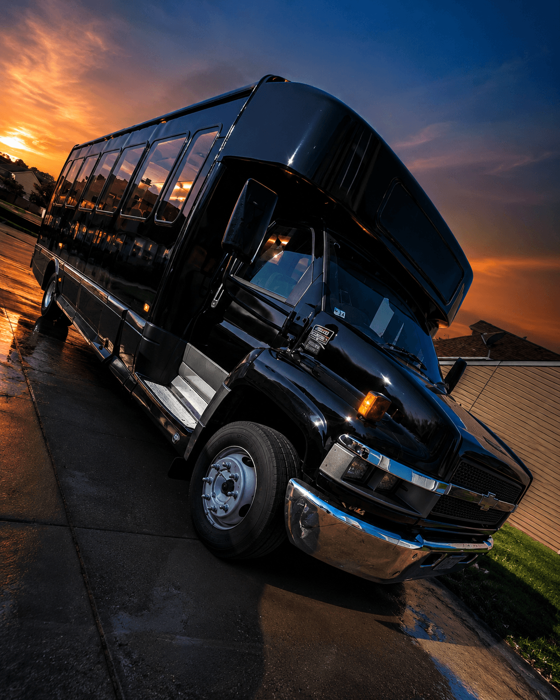 Triangle Party Wheels luxury black party bus glowing at sunset